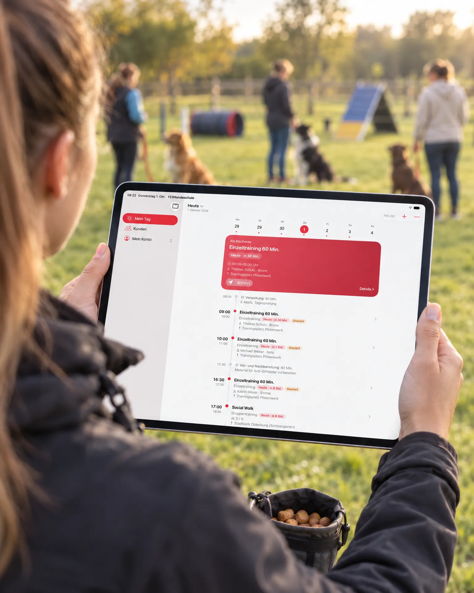 Trainerin auf dem Trainingsplatz mit iPad, auf dem Bildschirm die Tagesübersicht „Mein Tag“